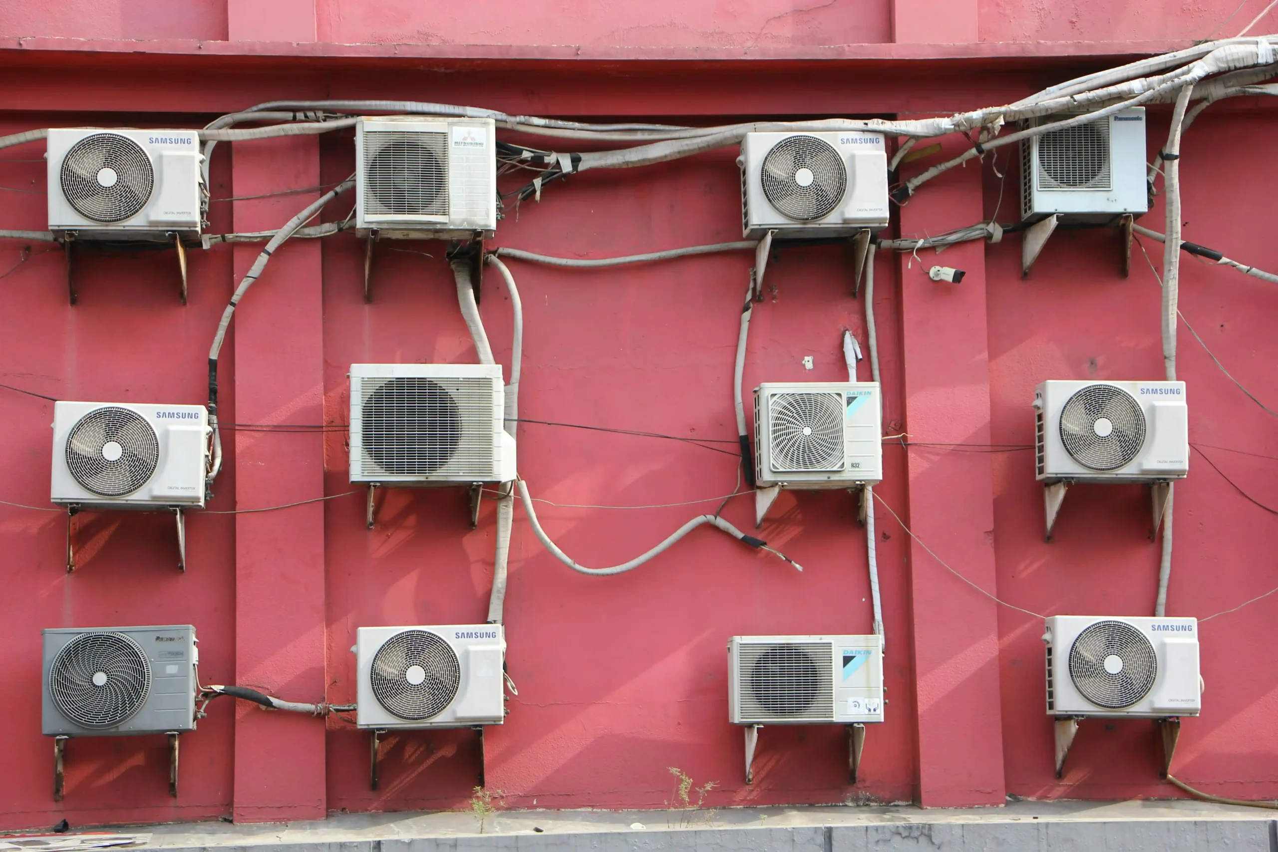 Technician installing a ductless split AC unit on a white wall