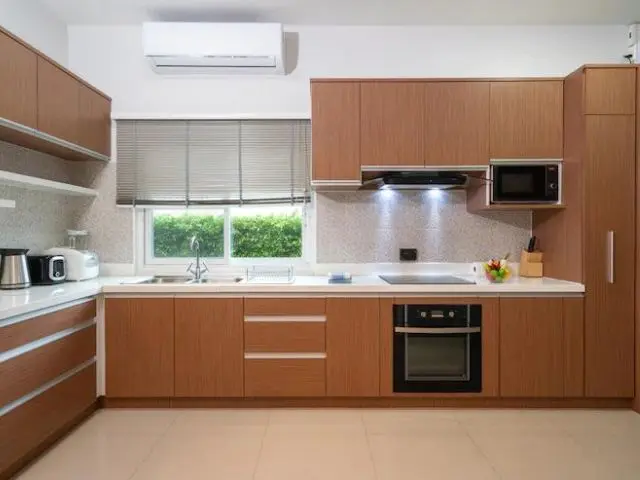 Technician adjusting built-in wall oven inside white kitchen cabinetry